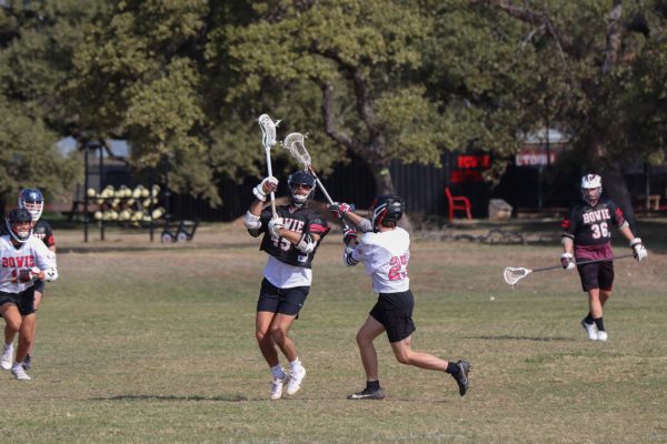 DEFENDING HIS PRIDE: Sophomore Haden Elley is defending against offensive coordinator coach Alex Gaskill in the lacrosse alumni game. It is a rivalry between the alumni and the current Bowie lacrosse players.