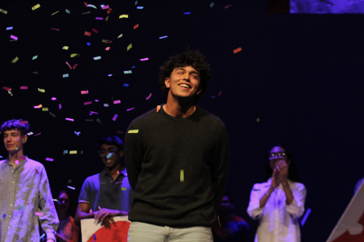 SINGER SHINES: Junior Louis Olmeda slowly watches the confetti fall after getting first place. Olemda received ballons, candy and the audience roaring for his singing talent.
