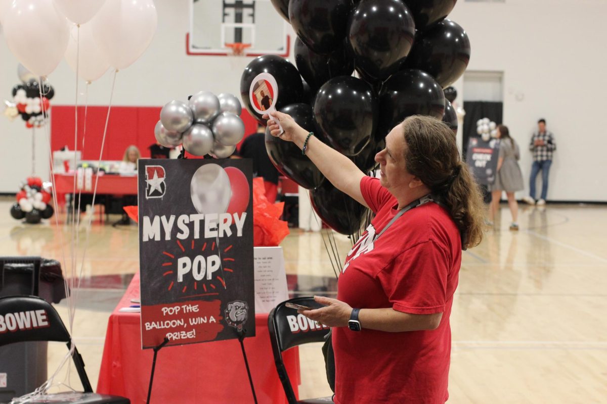 READY TO BID: A volunteer at the Bowie band fundraiser explains the rules to students for the balloon pop game. The balloon pop game was one of the features and events at the band fundraiser.