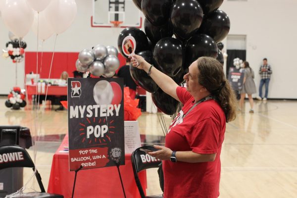 READY TO BID: A volunteer at the Bowie band fundraiser explains the rules to students for the balloon pop game. The balloon pop game was one of the features and events at the band fundraiser.