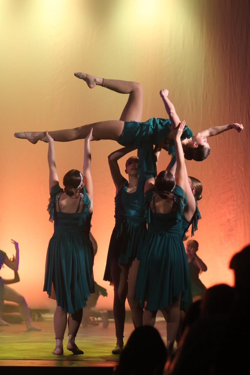 IN THE AIR: Showing their strength with their senior officer Finley Couch is held into the air showcasing her love for the sport and her muscle memory built through the countless hours of work. The Silver Stars powered through their last performance of the school year. “In the performance, I try my best to lay back on my fundamentals,” Couch said. “It was super sad after the performance, knowing it was last time I’d preform with my friends and my last performance of high school”