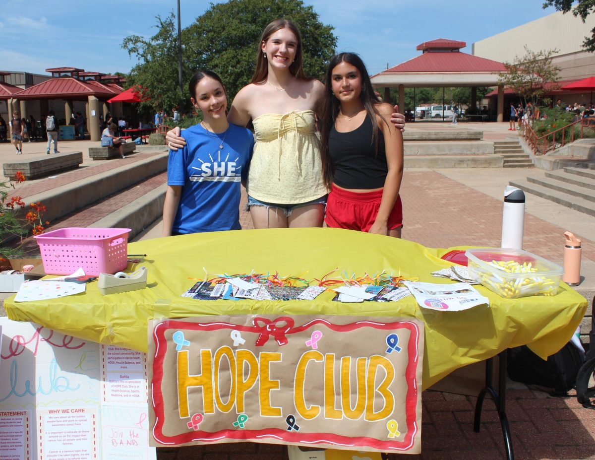 TURNING AWARENESS INTO ACTION: Sophomores Tess Sleeper, Madeline Adams, and Alisha Eveleigh stand together at the Hope Club booth. The Hope Club brings together students who are committed to making a positive impact in their community. “Hope Club’s purpose is to spread awareness about cancer,” sophomore Tess Sleeper said. “Usually people ever know about breast cancer, and we wanted to spread the idea that there’s more types of cancer people are affected by.”