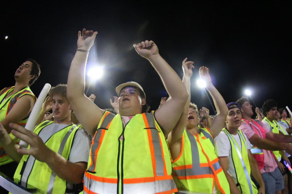 BRIGHTER THAN NEON: Spirit leader Easton Lewis cheers for his fellow Bulldawgs’ on the field and encourages his peers to light up the stands with neon decoration and vibrant energy. It was a Thursday night game, but the student section was still full of students sporting neon colors and lots of school pride.