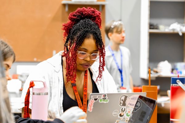 CREATIVE THINKING: Courtney Hall sits at a desk, eyes glued to her laptop. Hall returned to Bowie this year to teach technical theater.