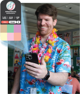 CHEESING FOR THE CAMERA: Chris Simons smiles down at his phone, just as he greets the teaching focused TikToks he makes.  Simons’ TikTok content varies from “day-in-the-life’s” to skits.