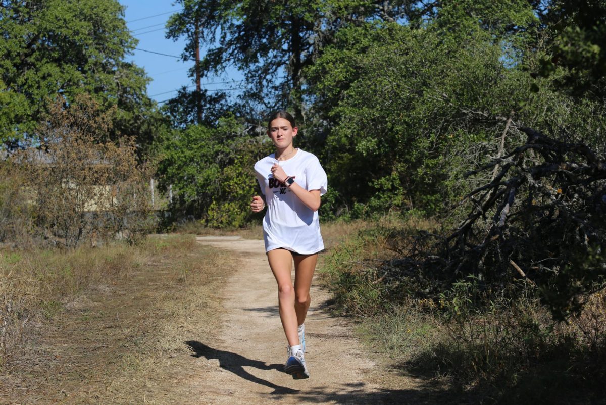 ONE MORE PUSH: Freshman Lilly Knauss sprints during her practice. The cross country team practices almost everyday to work on their running. 
