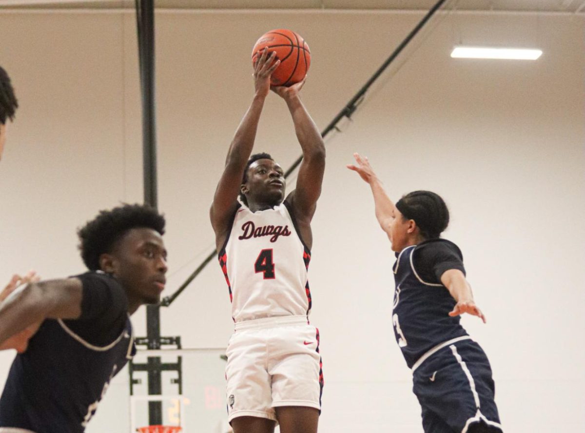FROM MID RANGE: Trying to sway the game into Bowie’s favor, junior Joshua Baskin puts a jump shot up from mid range. The Bulldogs would eventually go on to win this non-district game versus the Hendrickson Hawks with a final score of 83-78 in overtime, boosting the ‘Dawgs record to 9-1. “The main goal on offense is to remain calm,” Baskin said. “Offense should come naturally to you and should never be forced, thats when things go wrong.”  