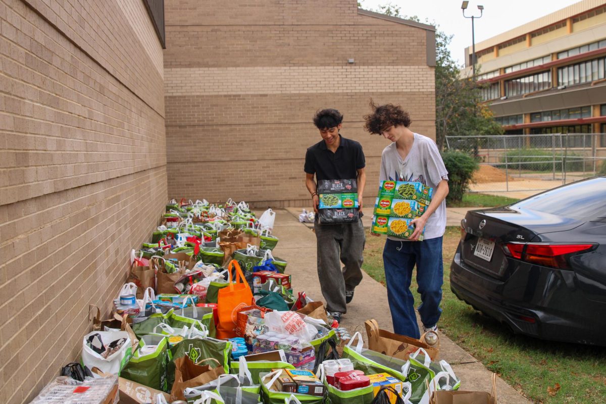 LINING UP THE DONATIONS: Student Council sponsor Alejandro Garcia's students Caleb Galvan and Liam Crowley helped student council members gather all the donated food at the end of the drive to take to the Central Texas Food Bank. Members filled up roughly twelve cars to transport all the donations.
