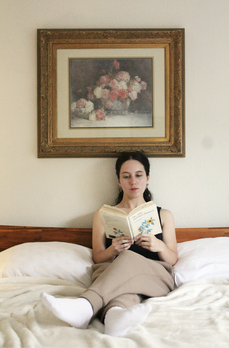 HEALING THROUGH WRITING: Emma Lopez sits reading her own self-published poetry book, “Through the Cracks, We Bloom.” Lopez started writing poetry to help process her feelings and document her mental health journey.