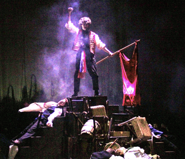 ONE LAST STAND: Sophomore Peter Davis stands on top of the barricade built by the hard working students. They started to work on the set since the beginning of the musical process and the barricade was a key element and important factor in the show.