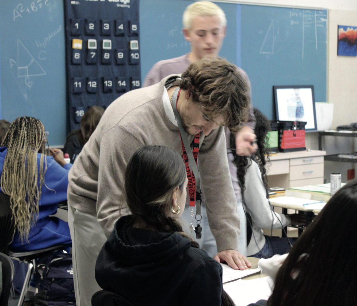 A HELPING HAND: Connor Bootz seen helping students with their assignments. With the departure of math teacher Davis Tran, Bootz took over his geometry classes shortly after the winter break. 