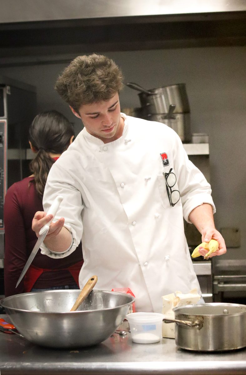 SLICING AND DICING: Junior Ryker Smith twirls his knife as he prepares to cut into a banana. Outside of his hobby and business for baking, Smith is also involved in the Bowie Culinary Program.