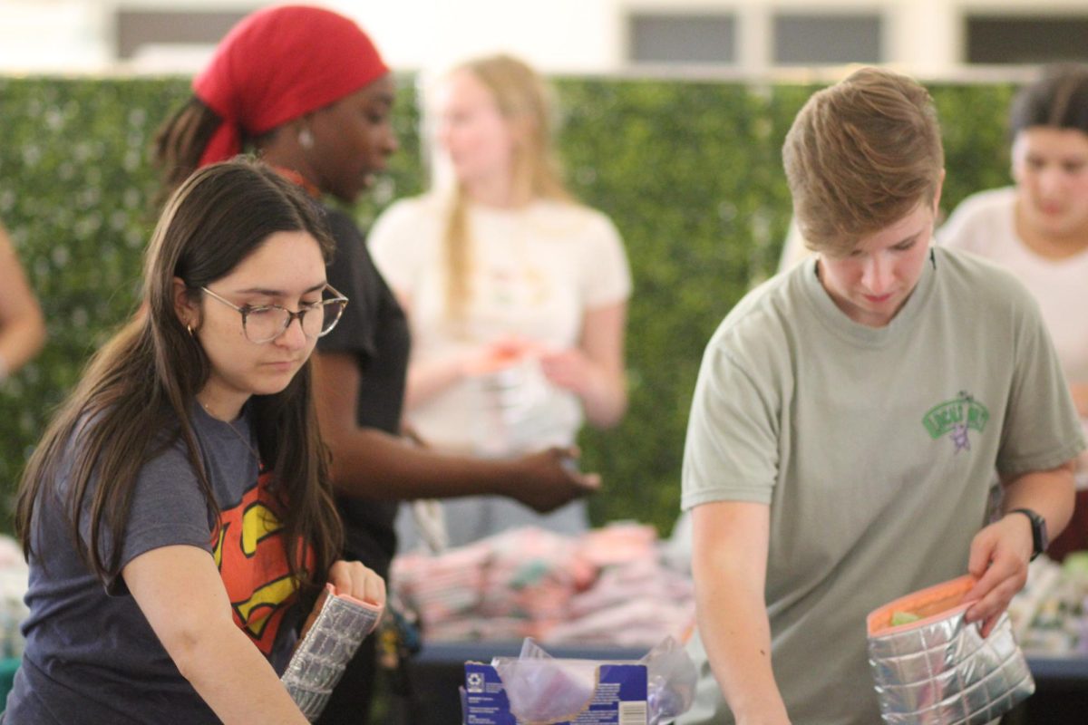PACKING PARTY: Junior Ella Parmer and senior Addison Fish place menstrual products into silver bags that will be shipped to those in need. The products were sent to I Support The Girls (ISTG) Austin where they will be distributed to several groups such as the homeless, at-risk youth and foster kids. 