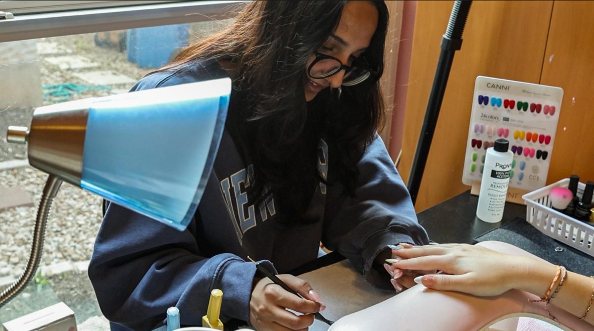 NEW PASSIONS: Senior Navika Amar bends over a nail set she shapes, paints, and designs. Artists like Amar and sophomore Bella Prieto do nails for themselves and peers, creating a community of entrepreneurs. 