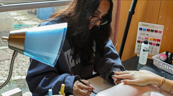 NEW PASSIONS: Senior Navika Amar bends over a nail set she shapes, paints, and designs. Artists like Amar and sophomore Bella Prieto do nails for themselves and peers, creating a community of entrepreneurs.