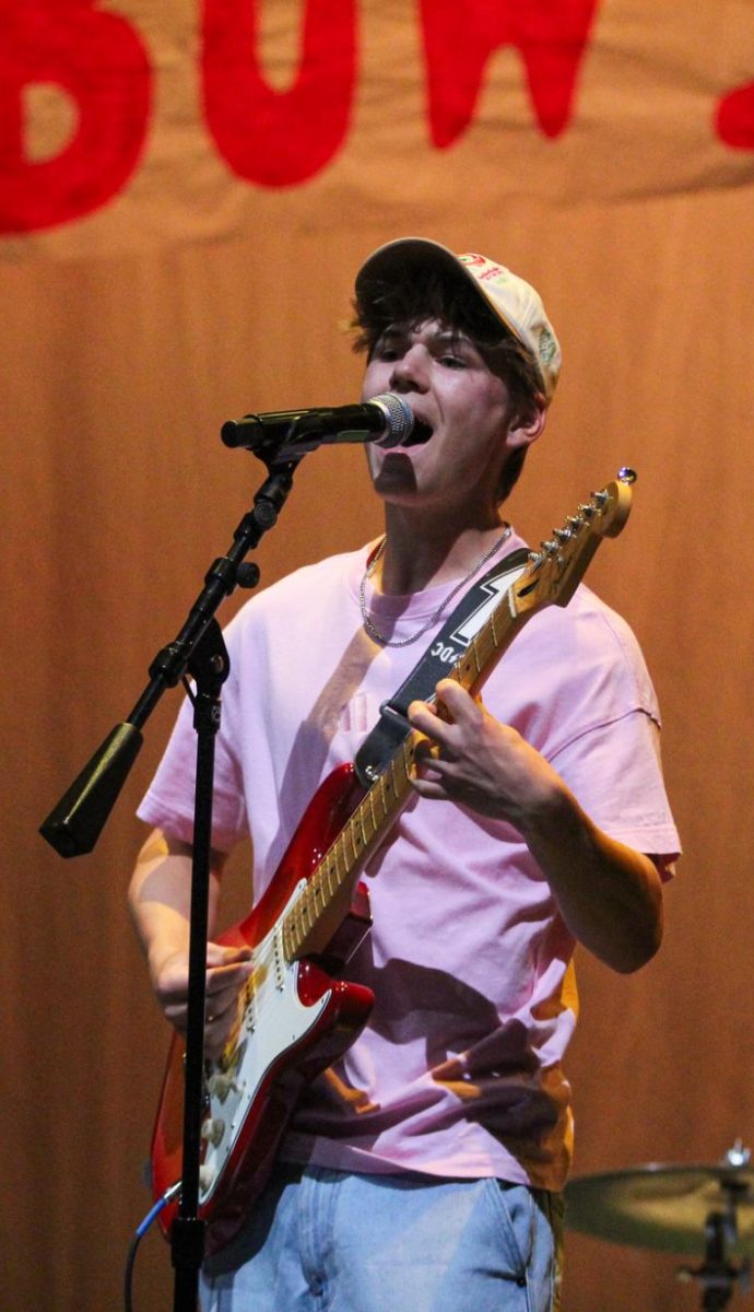 NO STRINGS ATTACHED: Junior Alex Doles holds onto his guitar and sings his own cover of “Valerie” by Amy Winehouse. Doles is part of a band called “The Fables” which includes other juniors and seniors. “I like taking a song people already know and making it feel a little different in my own way,” Doles said. “Playing guitar while singing at the same time makes it more challenging, so I have to really focus on timing and keeping everything smooth. Being in a band has helped me a lot with confidence and learning how to perform with other people, and doing a solo cover like this lets me bring that experience to the stage in a different way. It’s fun to see how people react to a song they already know but played with a new style.”

